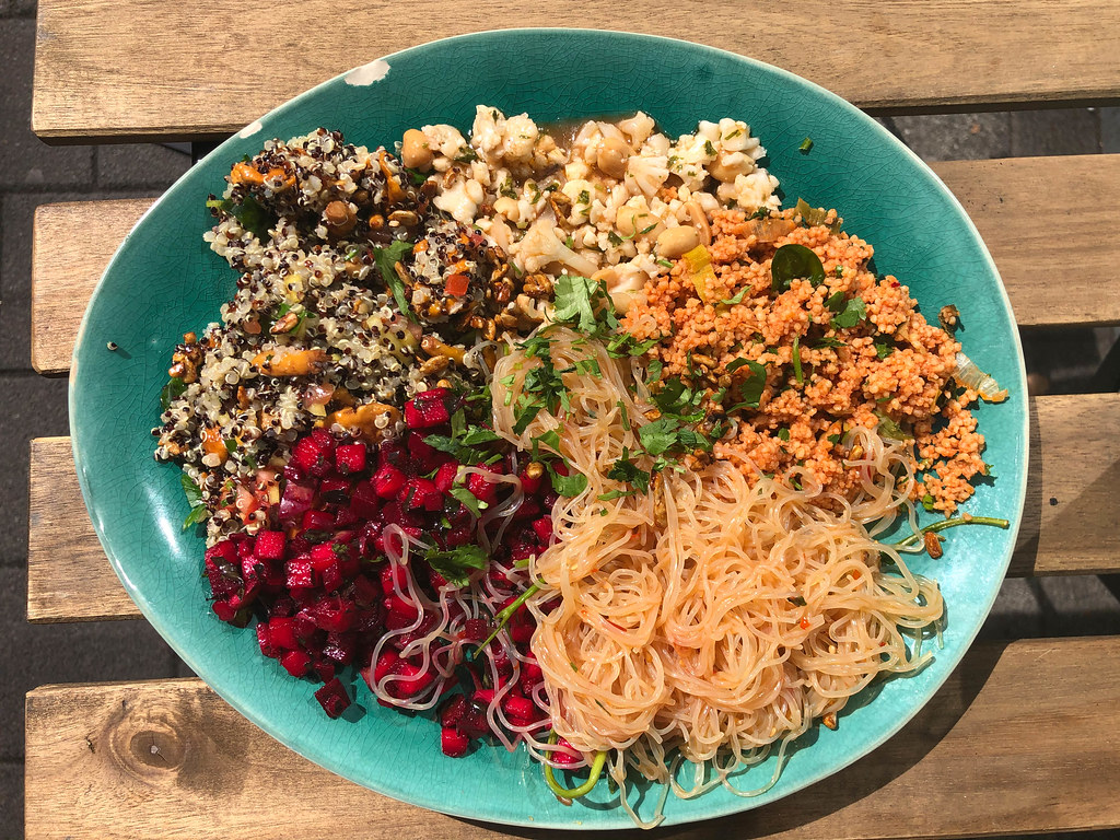 Obene Aufnahme von reichhaltigem veganen Bowl mit Couscous, Blumenkohlsalat, Rote Beete und Nudeln