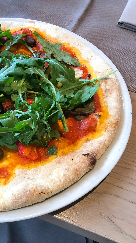 Close-up of an Italian-style pizza with tomato sauce, olives and a lot of rucola
