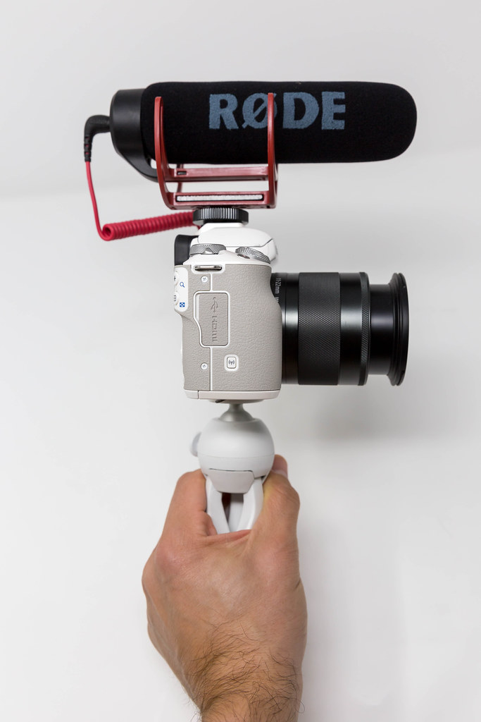 Männliche Hand hält eine Canon Kamera mit RØDE kompaktem Außenmikrofon - Seitenansicht