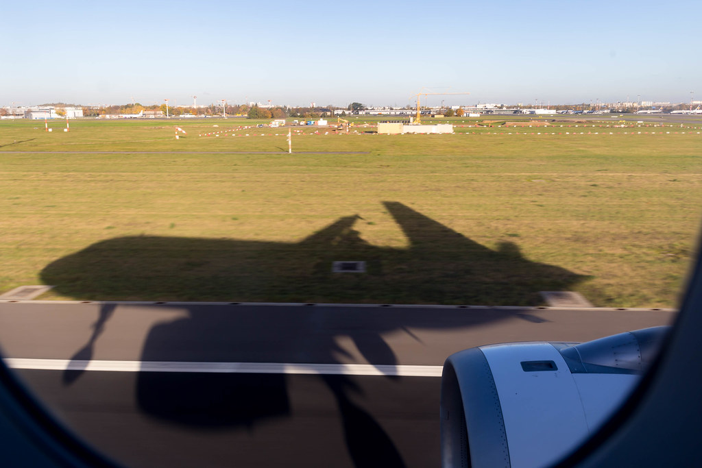 Airplane window view: shadow of plane landing for the first time at the finally opened BER airport, Berlin