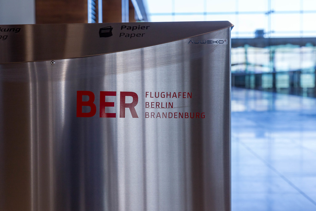 Nahaufnahme einer Mülltonne aus Metall mit BER Flughafen Berlin Brandenburg Logo in Rot