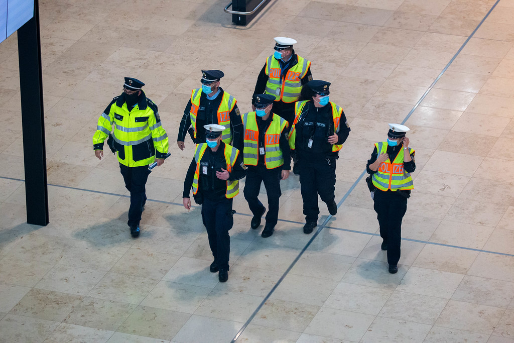Group of seven police officers wearing face masks and yellow high-visibility vests at new Berlin airport