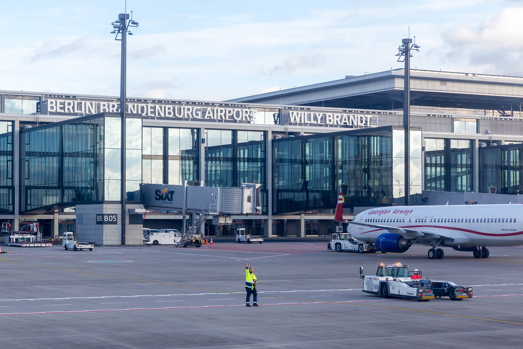 Flughafen BER: Mitarbeiter in Warnschutzjacke und Flugzeug von Georgian Airways auf dem Vorfeld