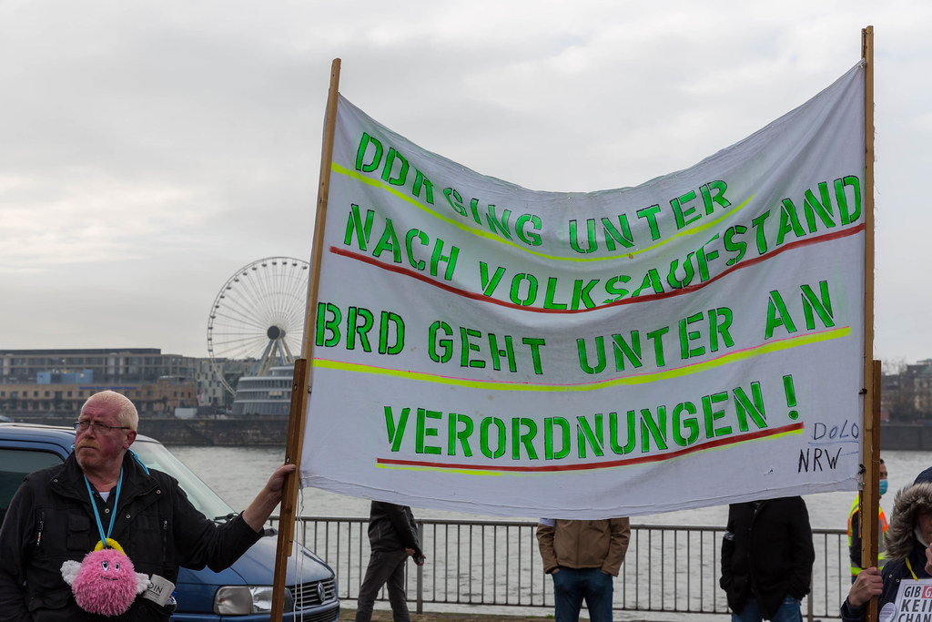 Anti-Corona-Demo in Köln: Demostrant ohne Mundschutz hält Schild gegen Corona-Verordnungen