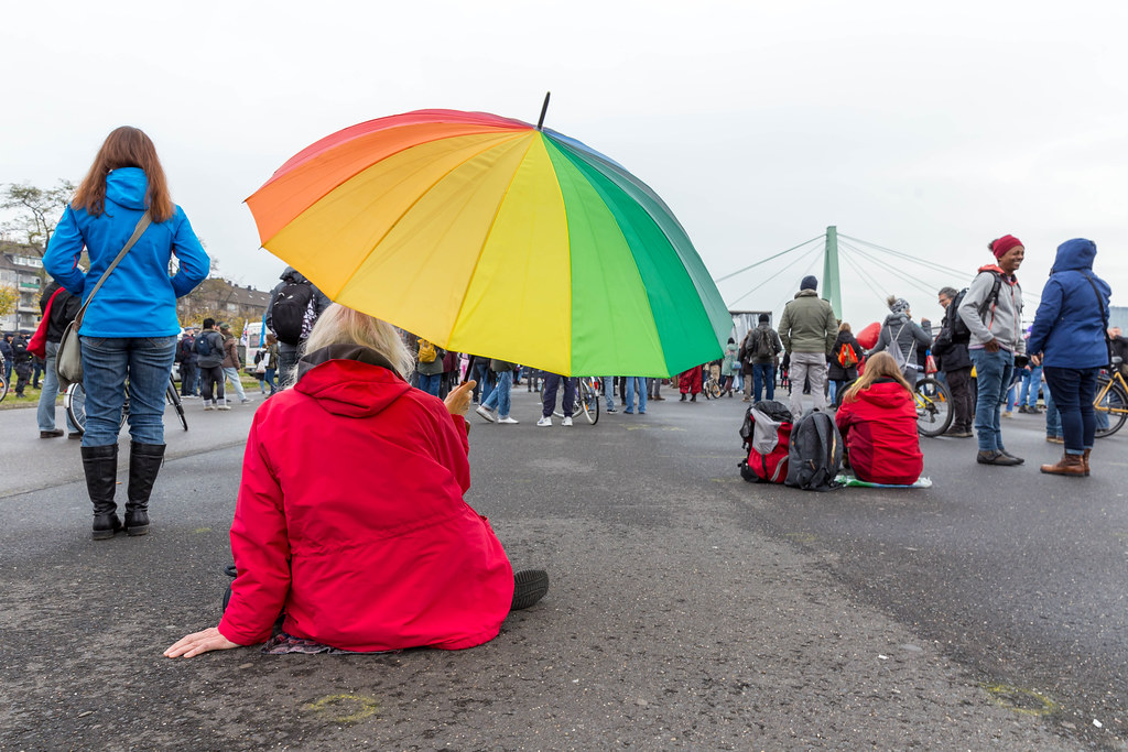 Regenbogen gegen Corona: Frau mit Regenbogen-schirm als Symbol für Frieden bei Anti-Corona-Demo