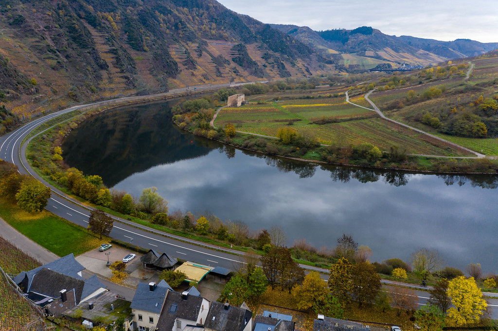 Aerial View of Federal Road B49 along River Moselle with Residential Buidlings and Hill Calmont Reflection in the River in Bremm, Germany