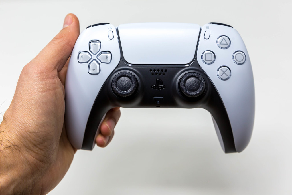 Front View of Person holding a White PlayStation 5 DualSense Wireless Controller on White Background