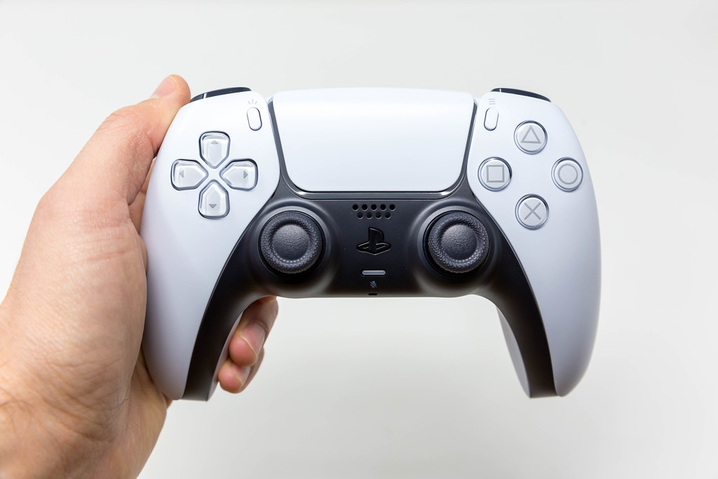 Person hält einen PlayStation 5 DualSense Wireless Controller in der Hand vor weißem Hintergrund
