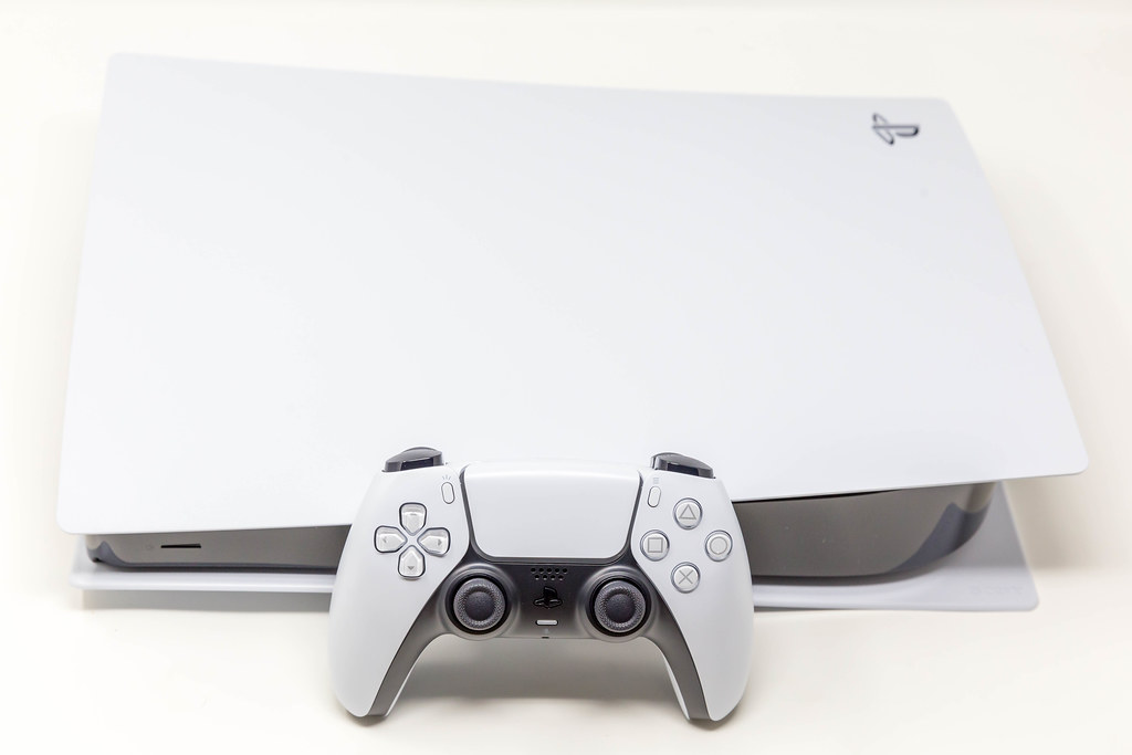 Sony DualSense Wireless-Controller vor einer liegenden Sony PlayStation 5 Digital Edition vor weißem Hintergrund