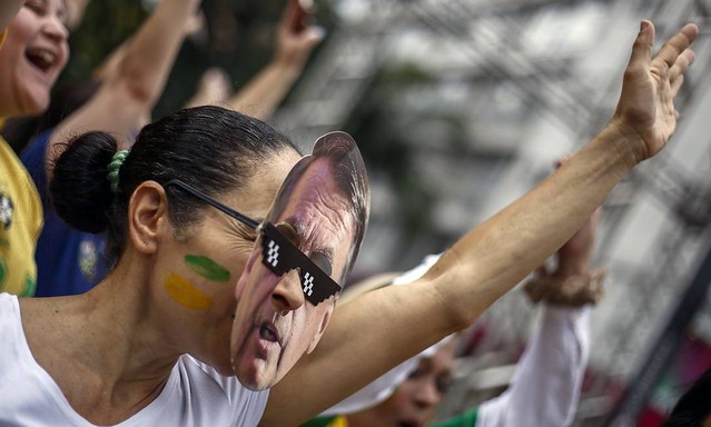 Manifestante protesta com a máscara do presidente Jair Bolsonaro (PSL) - Créditos: Miguel Schincariol / AFP