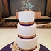 Three tiered gold and purple wedding cake with a cluster of roses