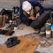 New Delhi, India - November 17, 2019: Indian craftsman (cobbler) fixes a broken zipper on a backpack in a market
