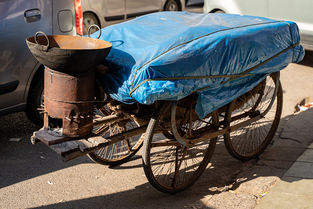 Traditional street cart with wok food cart in New Delhi India, parked on the side of a road, covered with tarp
