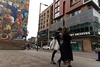 People walking past a building with a painting of people in colourful clothes (graffiti) in London. This image is provided on an as-is basis, royalty free for personal editorials, blogs and web display usage. - Royalty Free Urban Landscape