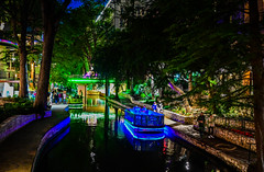 Blue lighted riverboat along the San Antonio Riverwalk at Night - San Antonio TX