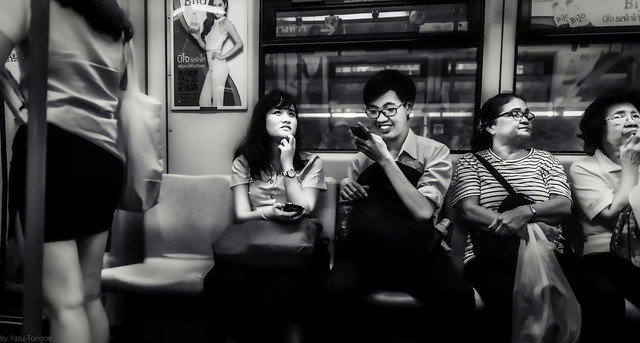 People using cell phones on a train at the Phrom Pong Subway station, Bangkok, Thailand.  782a