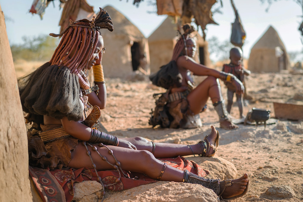 Femmes Himba assises devant leurs huttes dans un village traditionnel