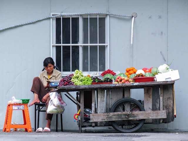 A vigilant female fruit vendor with her stall vehicle  deep in the alley