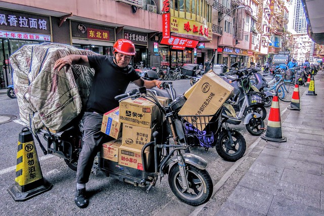 Courier trying to park his loaded scooter