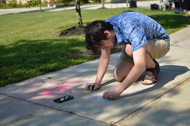 A student chalks the walk with a positivity message.