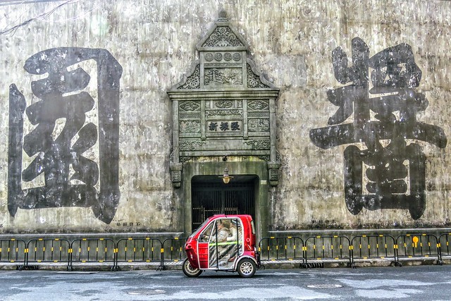 A passenger tricycle drives past a newly faked façade of a Republican-era soy sauce factory, whose existence in the history is not sure.